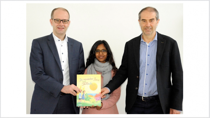 Das 1. Exemplar "Die wunderbare Reise nach Farbula" überreichten die Autorin Teresa George (Mitte) und Dr. Wolfram Geiger (rechts), Vorsitzende des Fördervereins Jollydent e.V., an Fulda-MdB Michael Brand und Vater von 3 Kindern